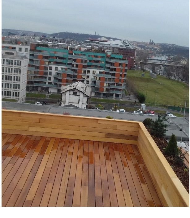 Roh střešní terasy s dřevěným soklem a panoramatem Prahy